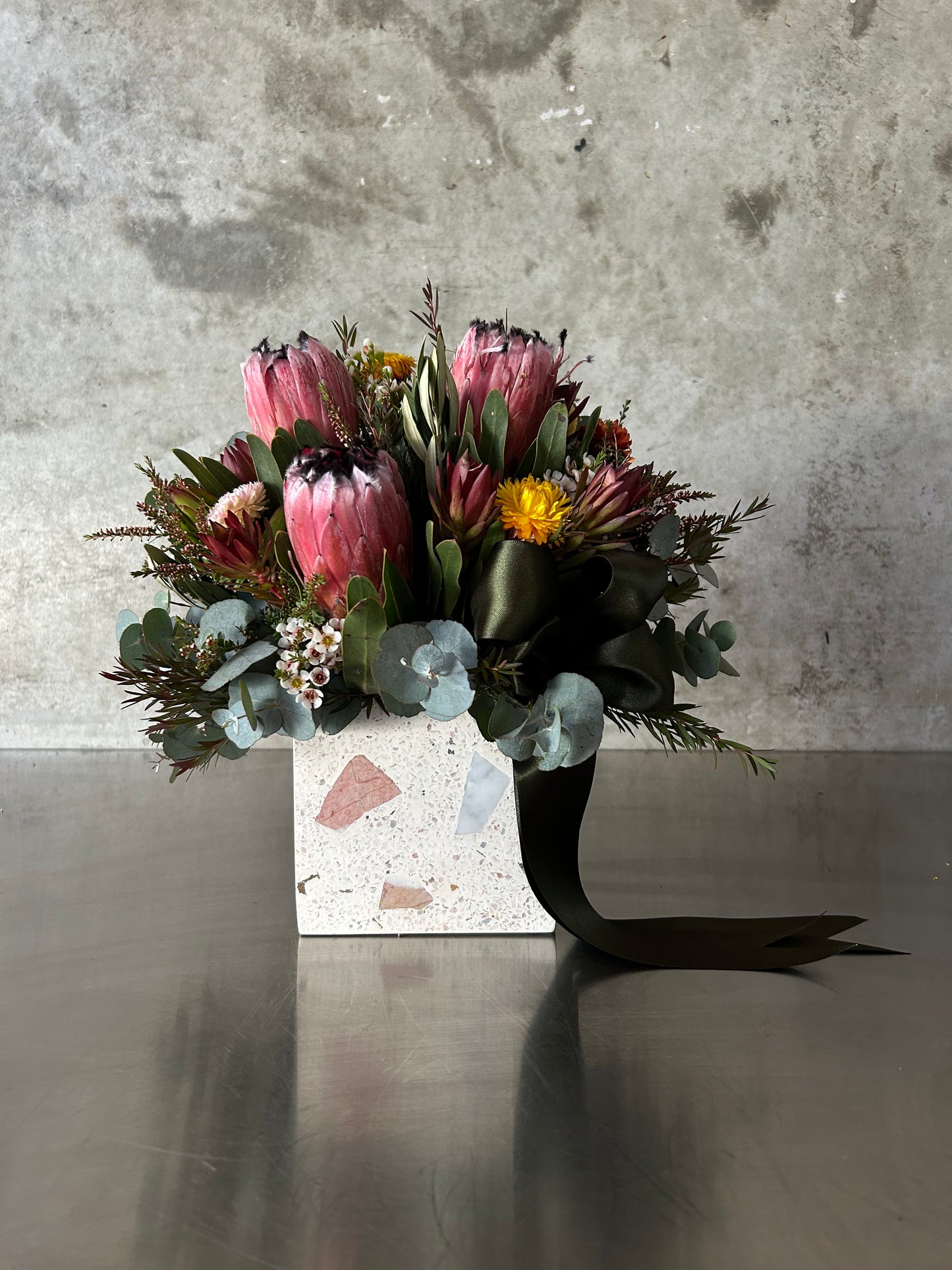 Jabiru wild protea box with native proteas, seasonal wildflowers and eucalyptus in a custom vessel, finished with a lush green ribbon.